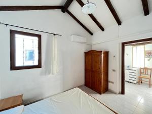 a bedroom with white walls and a window and a wooden cabinet at Appartamento Nassia 2 By La Via Del Mare Viaggi e Vacanze in Villasimius +7 photos