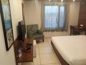 um quarto com uma cama, uma cadeira e uma televisão em Hotel Kanan em Ahmedabad