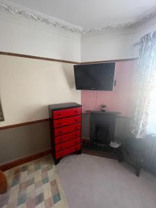 a room with a red dresser and a tv on the wall at Les Fleurs Accommodation in Dover