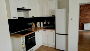 a kitchen with white cabinets and a white refrigerator at Przytulny Apartament w centrum miasta in Kętrzyn