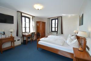 デッテルバッハにあるアクゼント ホテル フランツィスカナーのベッド、デスク、窓が備わるホテルルームです。