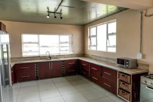 uma cozinha com armários de madeira, um lavatório e 2 janelas em 36 Emanzini Villa em Deneysville
