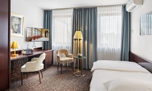アシャッフェンブルクにあるシティ - ホテル アッシャッフェンブルクのベッド、デスク、椅子が備わるホテルルームです。