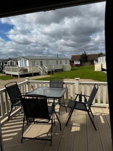 a patio with a table and chairs on a deck at Sunset Drive - Luxury caravan in Great Yarmouth