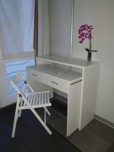 - un bureau blanc avec une chaise et un vase de fleurs dans l'établissement Ferienwohnung FeWo Rottweil -kleine Auszeit-, à Rottweil