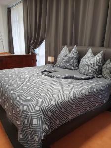 łóżko z czarno-białą kołdrą i poduszkami w obiekcie Ferienwohnung FeWo Rottweil -kleine Auszeit- w mieście Rottweil