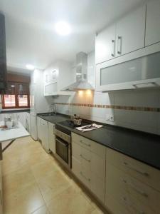 una cucina con armadi bianchi e piano di lavoro nero di Apartamento Jacaranda a Murcia