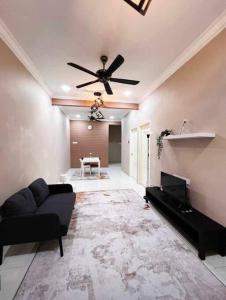 - un salon avec un canapé et un ventilateur de plafond dans l'établissement Rumah 127 - Homestay Taiping, à Simpang