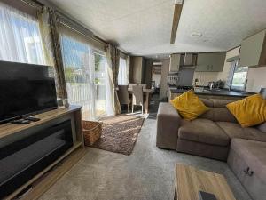 sala de estar con sofá y TV de pantalla plana en Beautiful 6 Berth Caravan At Breydon Water Nearby Great Yarmouth Ref 10056b en Belton