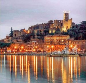 een stad met een stad op een heuvel met lichten op het water bij La Casina in Passignano sul Trasimeno