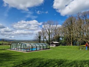 a glass greenhouse in a field with a soccer ball at Sandpiper Cottage in Llanboidy