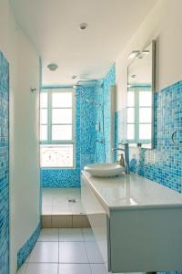 Baño azul con lavabo y espejo en Apartments Du Louvre - Le Marais, en París