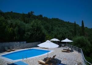 a swimming pool with chairs and umbrellas next to a mountain at Bellina Villa in Agnítsini