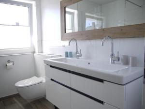 ein weißes Bad mit einem Waschbecken und einem WC in der Unterkunft Ferienhaus Haffliebe in Scharbeutz