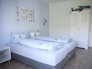 een witte slaapkamer met 2 bedden en gestreepte kussens bij Ferienhaus Haffliebe in Scharbeutz