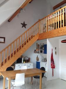 une salle à manger avec une table en bois et un escalier dans l'établissement Loft, terrasse au soleil - Vue mer, à deux pas de tout, à Wissant