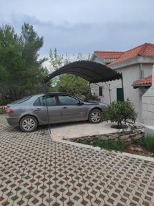 a car parked under an umbrella in a driveway at Obiteljska kuća za odmor Futura in Milna