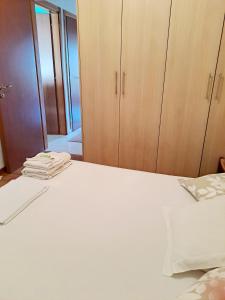 Schlafzimmer mit einem weißen Bett und Holzschränken in der Unterkunft Sea & City - 10 min drive to the beach & Athens Airport in Markopoulo
