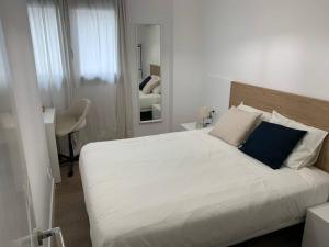 a bedroom with a large white bed with a blue pillow at Apartamento Central A in Algeciras