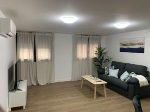 een woonkamer met een zwarte bank en een tafel bij Apartamento Central A in Algeciras