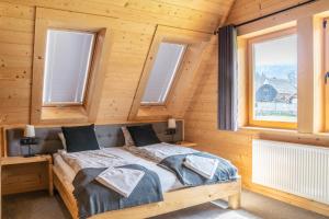 Cama en habitación de madera con ventanas en Domek Przy Dolinie, en Kościelisko