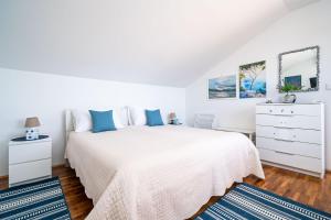 a white bedroom with a white bed with blue pillows at Guesthouse Slavka in Dubrovnik