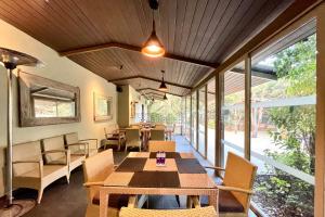 uma sala de jantar com mesa, cadeiras e janelas em Advait Resort Kshetra Mahabaleshwar em Mahabaleshwar
