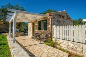 una pequeña casa de piedra con una valla blanca en Ranias Case Dell Olivetto en Gaios