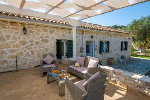 un patio con muebles y una pared de piedra. en Ranias Case Dell Olivetto en Gaios