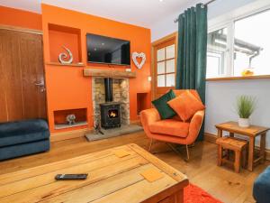 - un salon avec des murs orange et une cheminée dans l'établissement Bluebell Cottage, à Ulverston