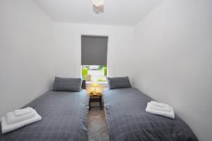 2 łóżka pojedyncze w pokoju z oknem w obiekcie The Grove w Edynburgu