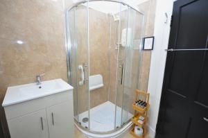 une douche avec une porte en verre à côté d'un lavabo dans l'établissement The Grove, à Édimbourg