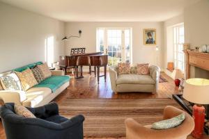 sala de estar con sofá y piano en Wolford Lodge Traditional home surrounded 150 private acres with Tennis court, en Honiton