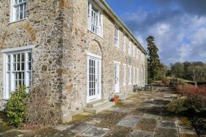 an old stone building with white windows on it at Wolford Lodge Traditional home surrounded 150 private acres with Tennis court in Honiton