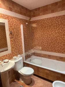 a bathroom with a toilet and a tub and a sink at HOSTAL CHIQUININO II in Higuera la Real