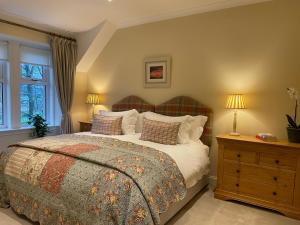 a bedroom with a bed and two lamps and a window at Luxury Garden Cottage in Dalry