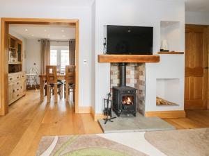 Primrose Cottage في أولفيرستون: غرفة معيشة مع موقد وتلفزيون فوقها