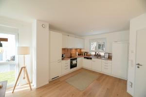 una cucina con armadietti bianchi e frigorifero bianco di LIBORIA: Stylisches Haus; Sauna ; 4min zum See a Seehausen am Staffelsee