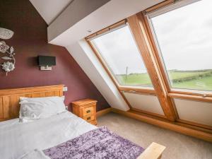 a bedroom with a bed and two large windows at Primrose Cottage in Ulverston