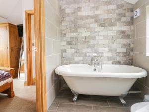 eine Badewanne im Bad mit Ziegelwand in der Unterkunft Primrose Cottage in Ulverston + 23 Fotos
