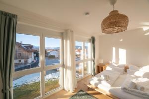 a living room with a white couch and large windows at LIBORIA: Stylisches Haus; Sauna ; 4min zum See in Seehausen am Staffelsee