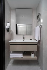 W białej łazience znajduje się umywalka i lustro. w obiekcie Pianoforte by Febor Hotels&Spa w Stambule
