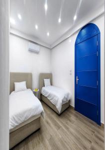 two beds in a room with a blue door at Lara Family Resorts in Mukāwir