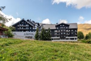 a building on a hill with a green field at CGH Résidences & Spas Alpaga in La Toussuire