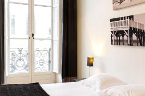 a bedroom with a bed and a window with a balcony at Condillac - Appartement 2 chambres avec ascenseur et Parking in Bordeaux