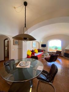 uma sala de estar com uma mesa de vidro e cadeiras em Villa Sea view con terrazza e giardino em Capri