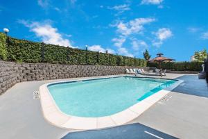 una piscina con una pared de piedra y un cielo azul en Super 8 by Wyndham Weatherford, en Weatherford