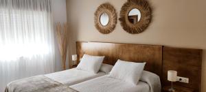 een slaapkamer met een bed en twee spiegels aan de muur bij Hostal O Forno in O Barqueiro