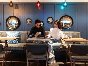 un homme et une femme assis à une table dans un restaurant dans l'établissement ibis Amsterdam Centre, à Amsterdam