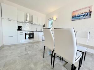 uma cozinha branca com cadeiras brancas e uma mesa em Palit Hills Superior Apartments em Rab